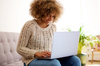 woman sitting on a couch at home with laptop on her lap