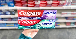 hand holding two boxes of Colgate toothpaste