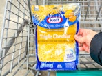 hand holding a bag of kraft shredded cheese
