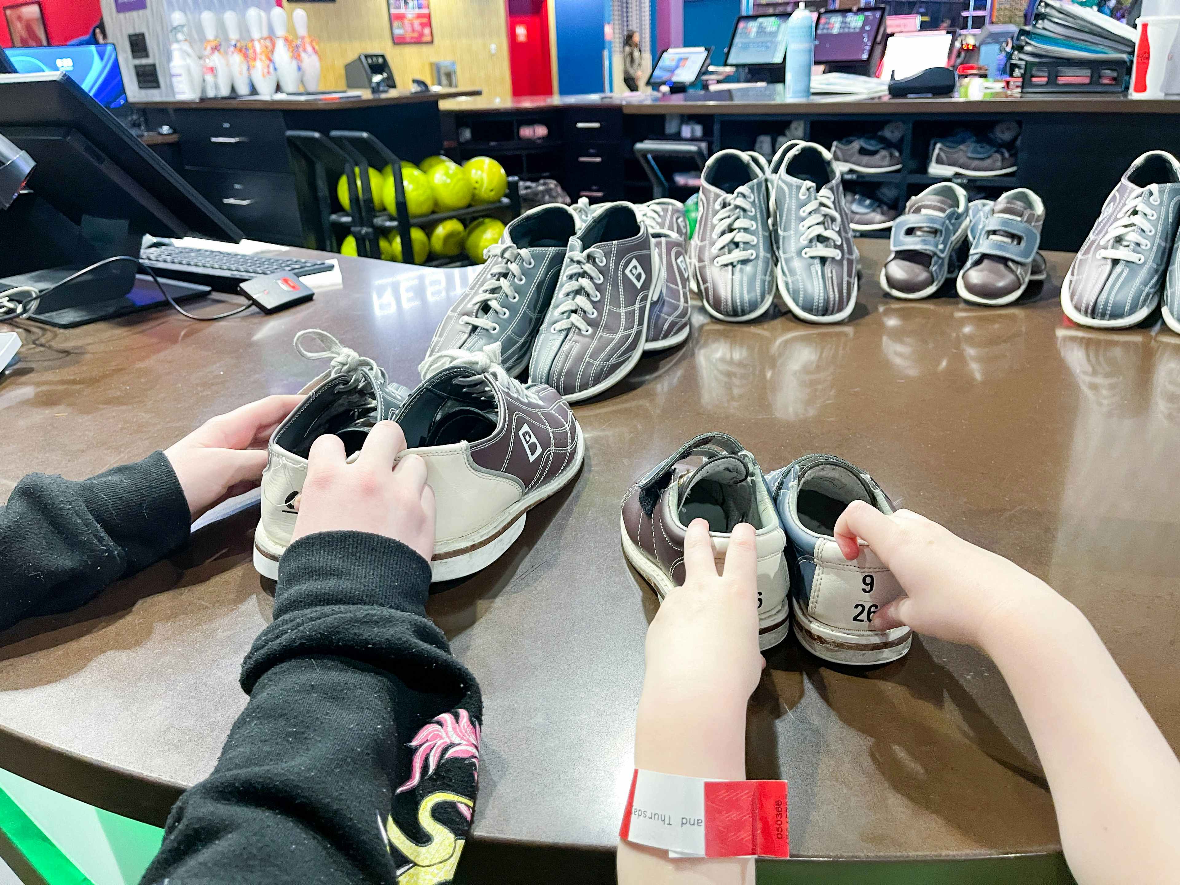 two children's hands putting away bowling shoes 