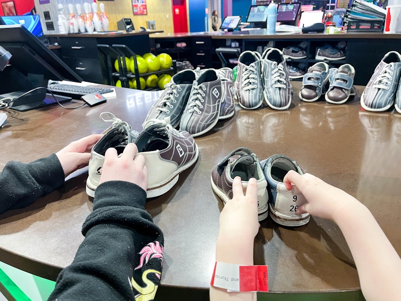 two children's hands putting away bowling shoes 