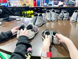 two children's hands putting away bowling shoes