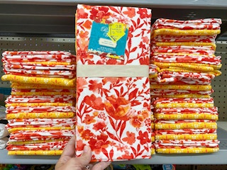 The Pioneer Woman Kitchen Towels held in front of shelf at Walmart. Clearance sticker reads $3, regularly $5.94.