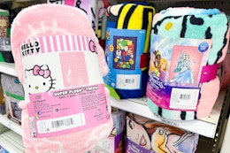 hand holding character throw blankets in front of a target shelf