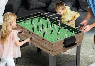 children and adult playing fooseball on a game table