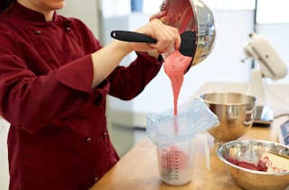 A woman pouring batter with a spatula in the kitchen