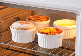 Four ramekins inside an oven with food in them