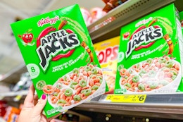 hand holding a box of kellogg's apple jacks cereal at dollar general
