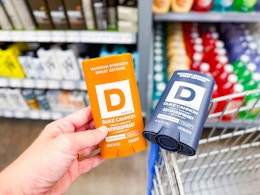 hand holding a duke cannon deodorant next to another one on walmart cart
