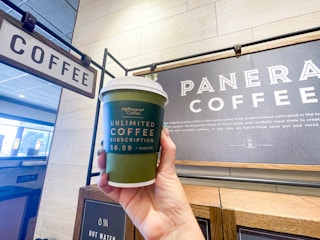 panera coffee being held in front of sign in store 