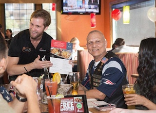 Elderly man with family and server inside Applebee's resturant