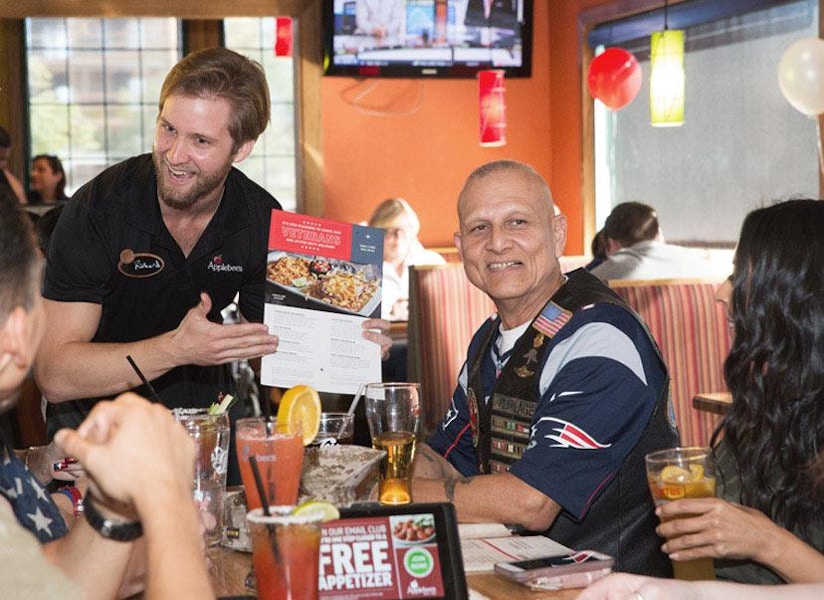 Elderly man with family and server inside Applebee's resturant