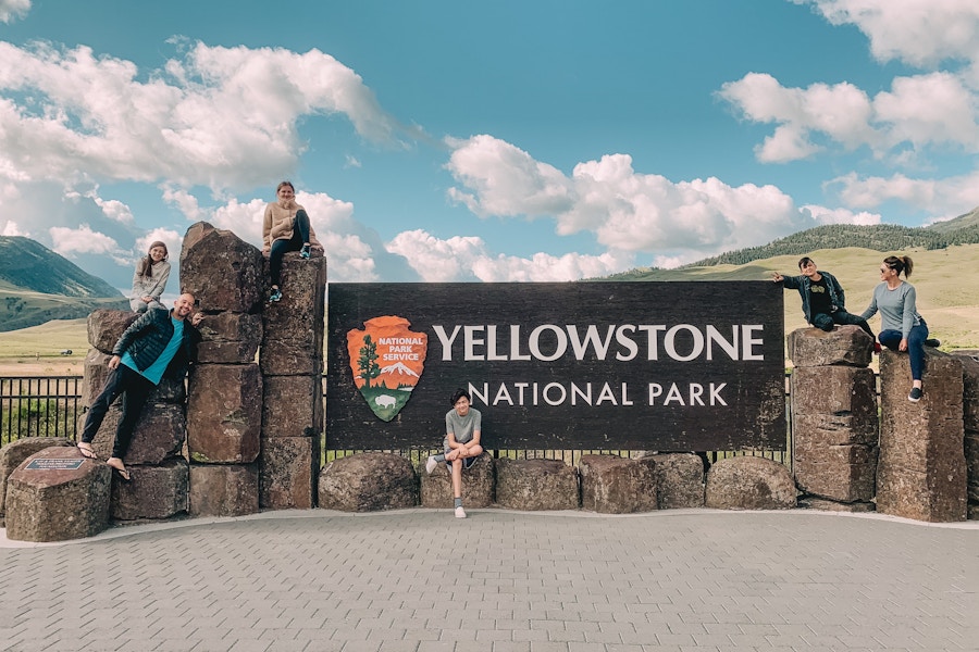 Family posing on the Yellowstone national park sign