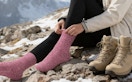 a person putting on pink wools socks on a mountain