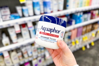 a hand holding a jar of body cream