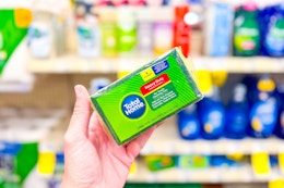 person holding a pack of sponges in front of the shelf