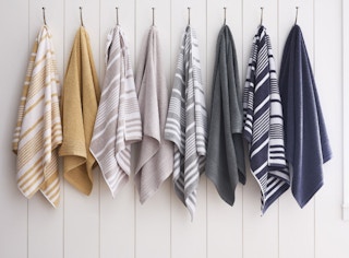 solid and striped bath towels hanging on racks in a row