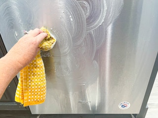 person using dishcloth to clean dishwasher