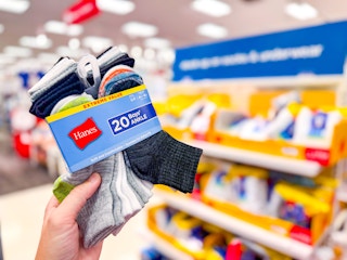 hand holding a pack of hanes kids socks in front of a display at target