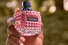 a woman holding a bottle of valentino donna born in roma perfume