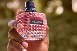 a woman holding a bottle of valentino donna born in roma perfume