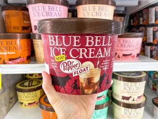 Someone holding Blue Bell Dr. Pepper Float ice cream in front of a store shelf