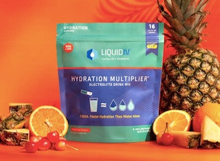liquid iv bag with tropical fruits next to it like pineapples and oranges