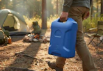 person carrying a blue 6-gallon watering jug to a camp site