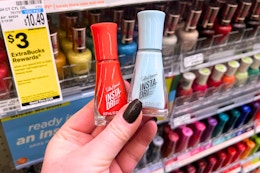 person holding 2 sally hansen nail polishes
