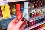 person holding 2 sally hansen nail polishes