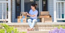 a person sitting on a front porch smiling while holding amazon boxes