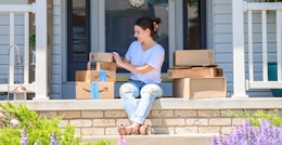 a person sitting on a front porch smiling while holding amazon boxes