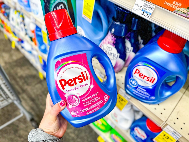 person holding a bottle of persil laundry detergent by a shelf