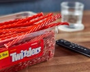 a container of Twizzlers next to a remote