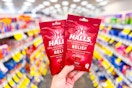 person holding 2 bags of halls cough drops in an aisle