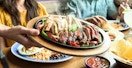 on the border server placing plate of fajitas on table in restaurant