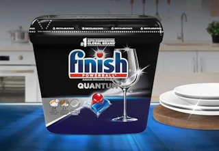 a tub of dishwasher pods on a table with dishes