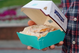 Someone holding a Cinnabon cinnamon roll in a box