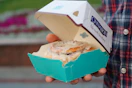 Someone holding a Cinnabon cinnamon roll in a box