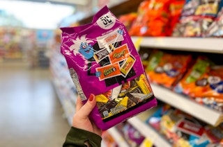 person holding a bag of halloween candy in an aisle