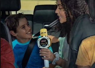 a woman and a boy using a carpool karaoke microphone in the car