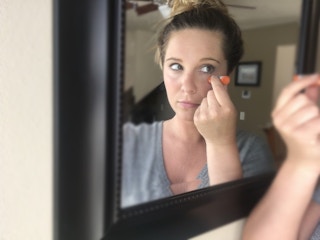 Woman applying lip balm below her eyes