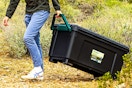Lifestyle image of the Remington 42 gal Plastic Storage Bins with Lid being pulled outdoors