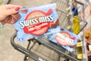 person placing swiss miss hot chocolate mix in a cart