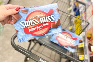 person placing swiss miss hot chocolate mix in a cart
