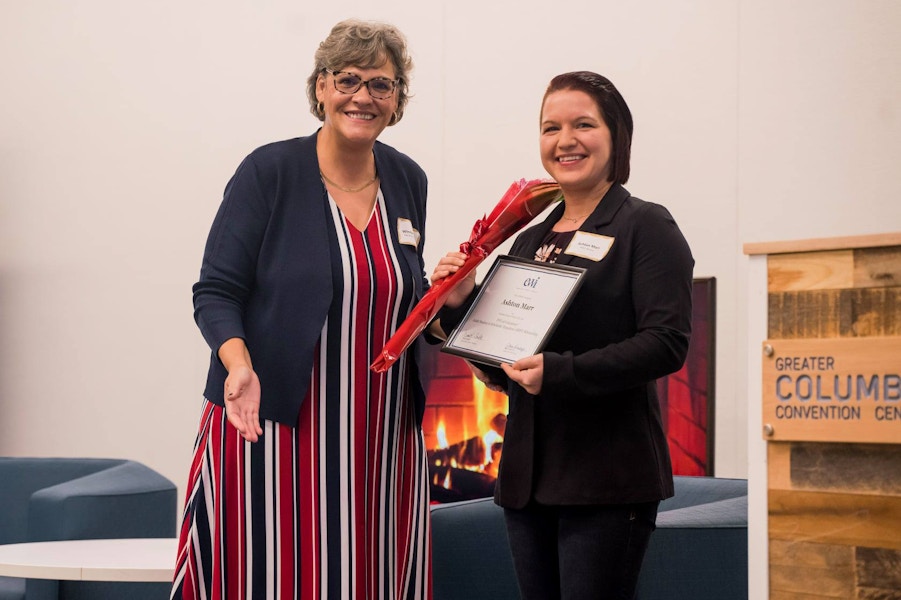 The EWI ASIST scholarship winner being awarded a certificate on stage.