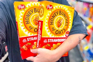 person holding 2 boxes of honey bunches of oats cereal