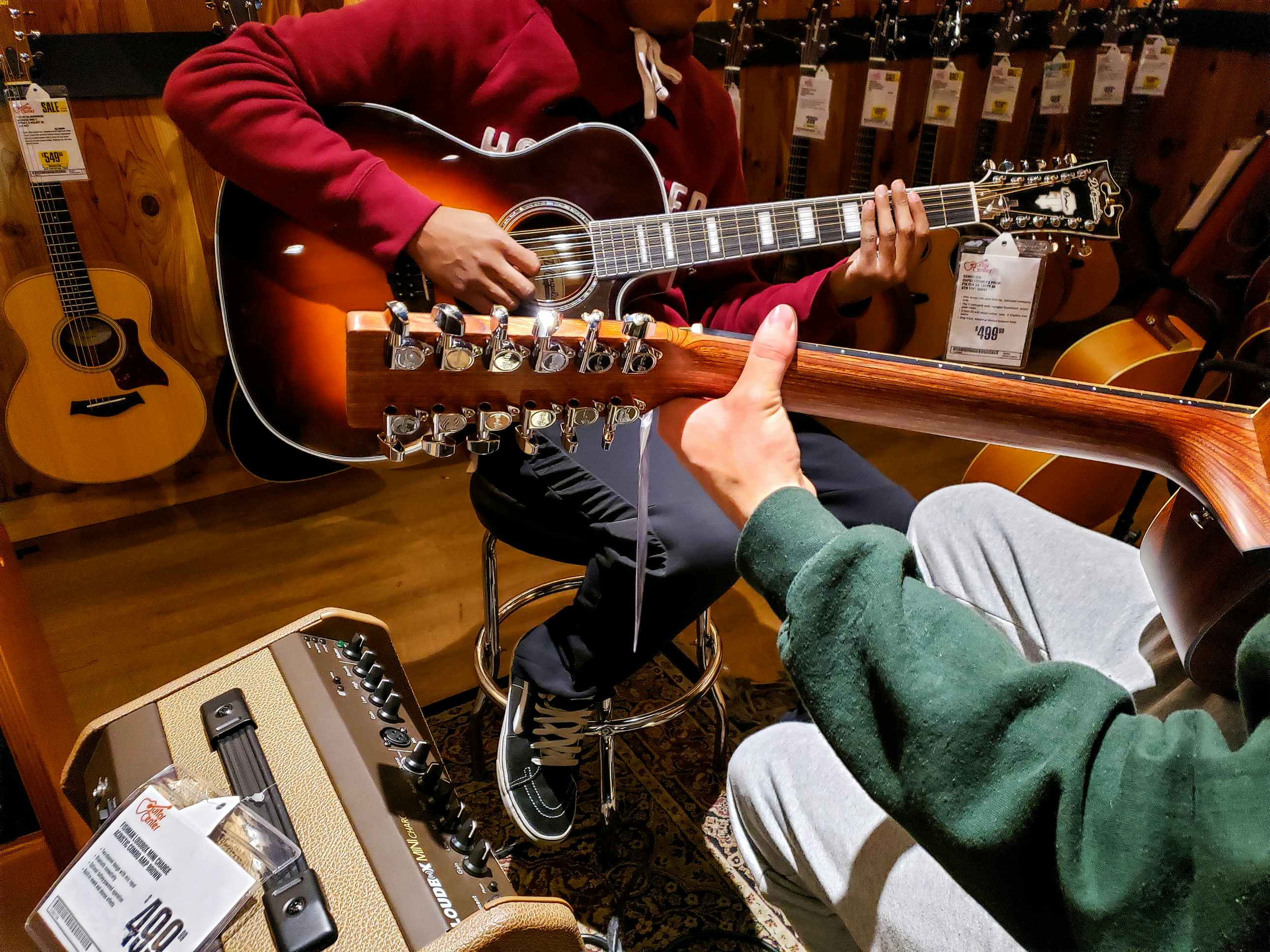 two people playing guitars in guitar center