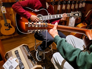 two people playing guitars in guitar center