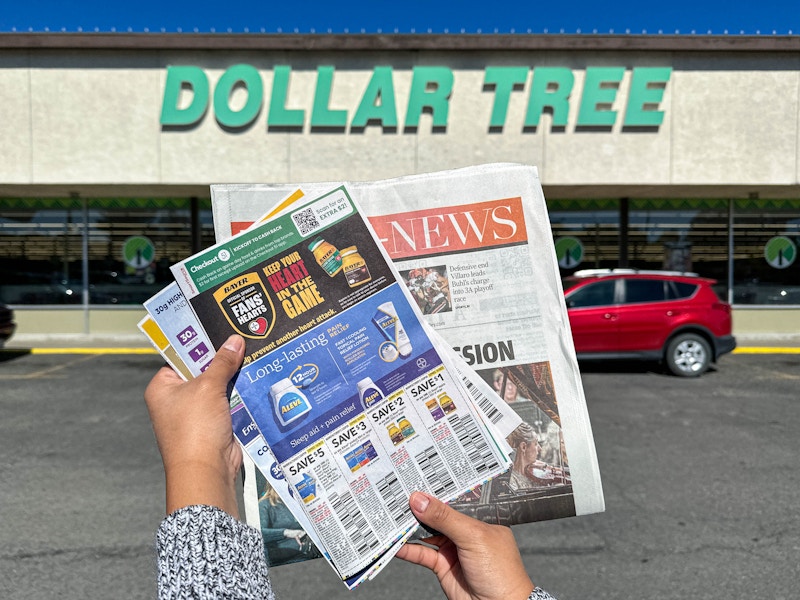 a person holding a newspaper outside dollar tree 